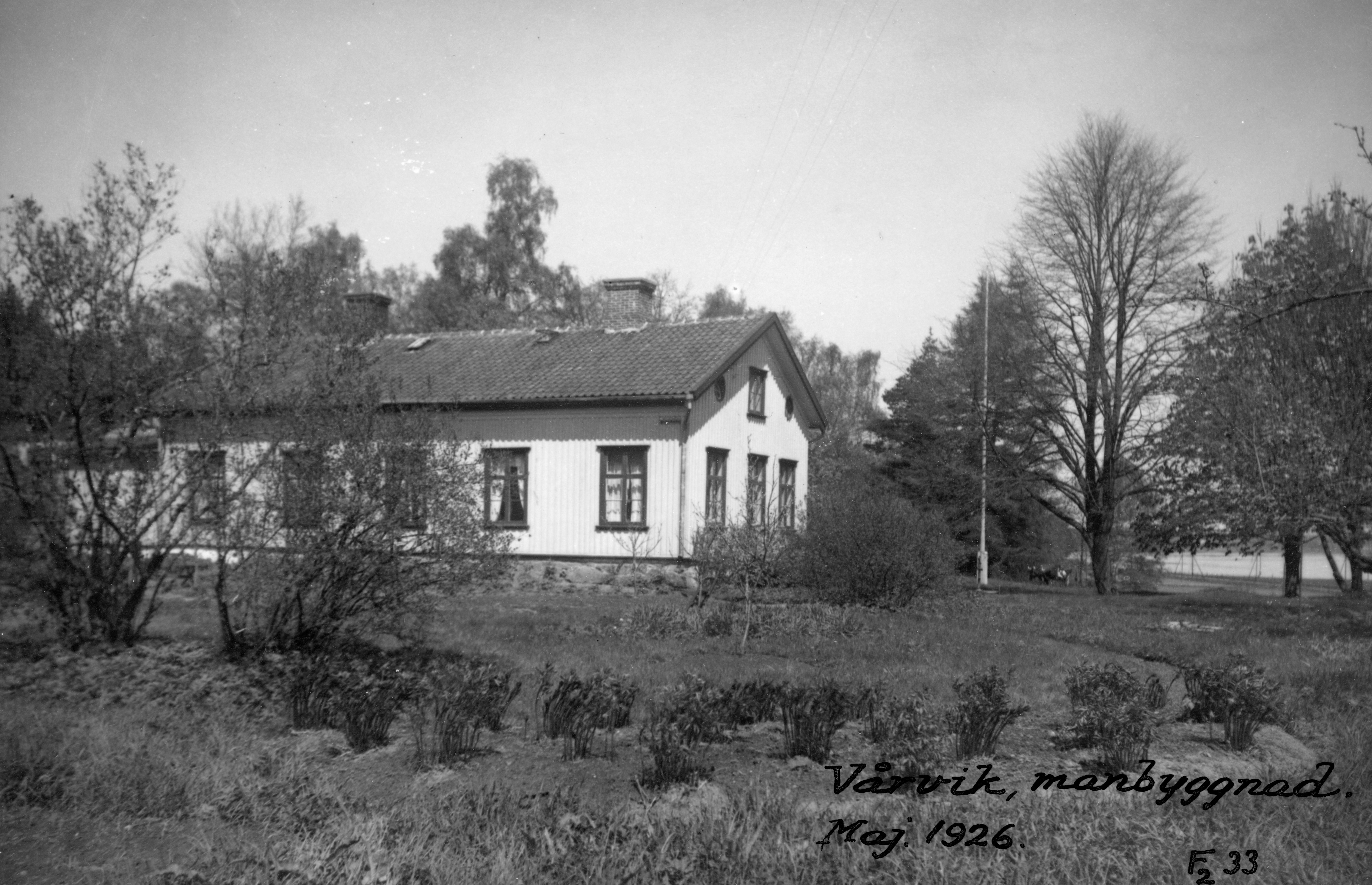 Svartvit bild på ett hus med många fönster.  Runt huset syns mycket grönska.