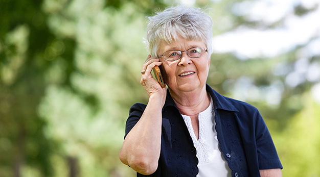 Äldre kvinna som pratar i sin mobil