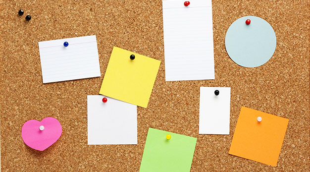 Analog anslagstavla i kork, med massor av post-it-lappar på