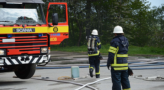 Brandman som står bredvid en brandbil