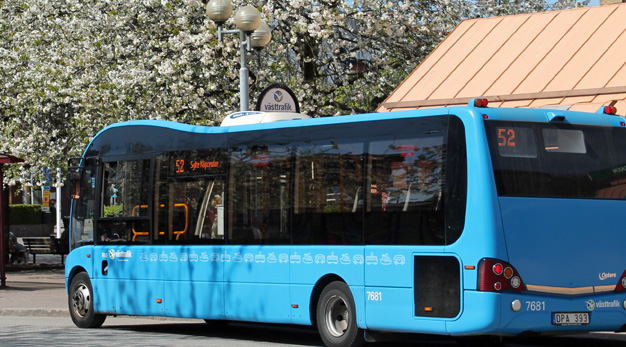 Blå stadsbuss, blommande träd i bakgrunden