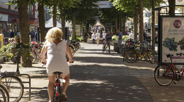 Bild från centrala centrum i Trollhättan. Kvinna som cyklar i förgrunden.