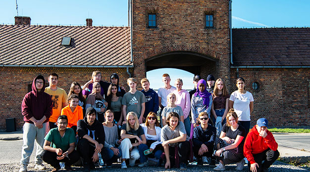 Elever från Trollhättans Stads skolor framför koncentrationslägret Birkenau 2019. Nathalie Wedel, tredje person från vänster längst fram.