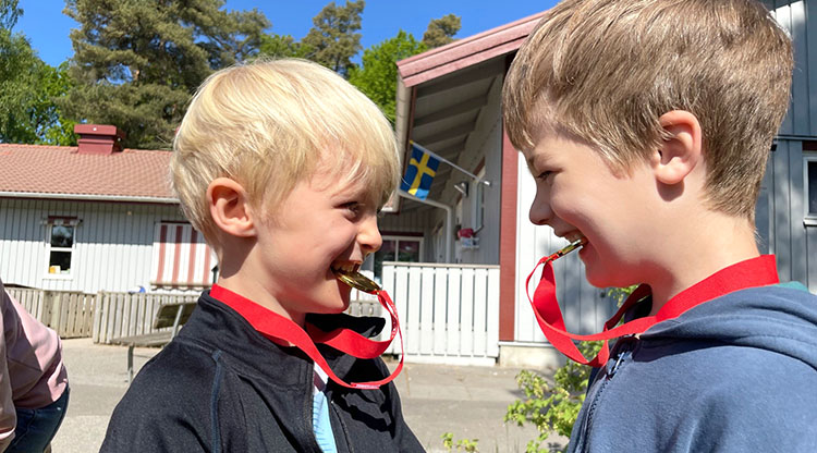 Två barn som biter på varsin medalj