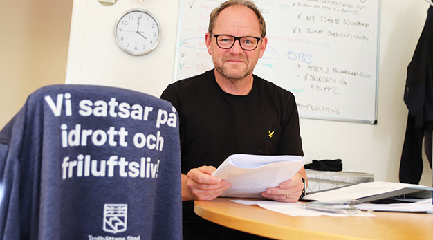 Robert Stenberg med jacka i förgrunden med texten "vi satsar på idrott och friluftsliv"