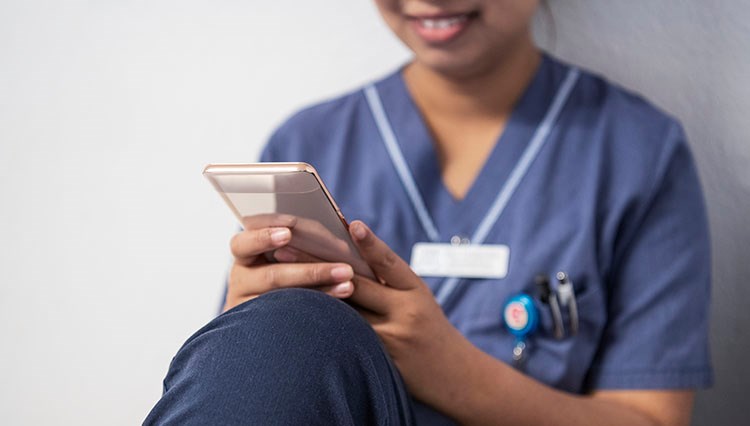 Person i vårdkläder tittar på sin telefon