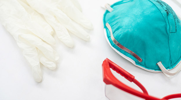 Skyddsutrustning inom vården - röda skyddsglasögon, blått munskydd och vita plasthandskar