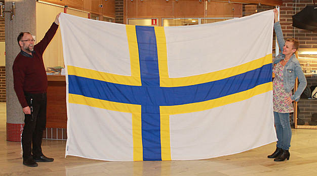 Två personer håller upp den Sverigefinska flaggan, receptionen, Stadshuset.