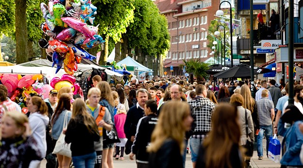 Vimmelbild i sommarcity, massor av folk och ballonger i action