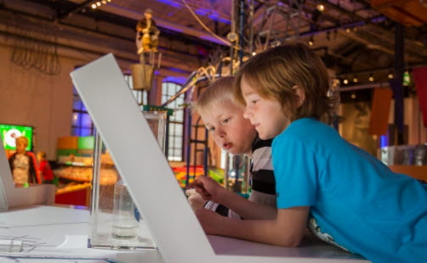 Två pojkar i åttaårsåldern gör ett lekfullt experiment i barninriktad labbmiljö. Foto.