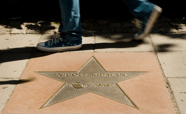 Guldfärgad metallstjärna på gatan med Nicole Kidman som inskription. Person med jeans passerar förbi stjärnan. Foto.