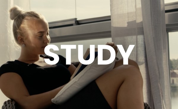 Kvinnlig student läser en bok, vid ett fönster med utsikt över vatten. Bildtext säger Study. Foto.