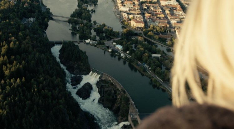 Kvinna tittar ner över Trollhättans fall från hög höjd. Foto.