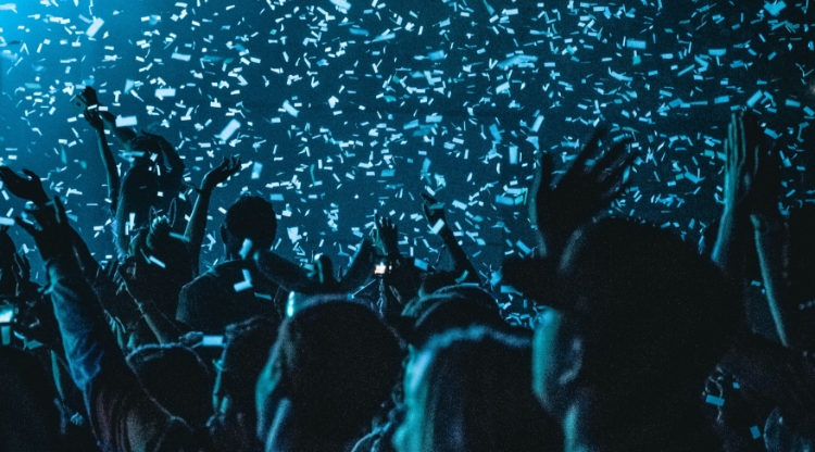 Konfettiregn över publikhav i mörker. Foto.