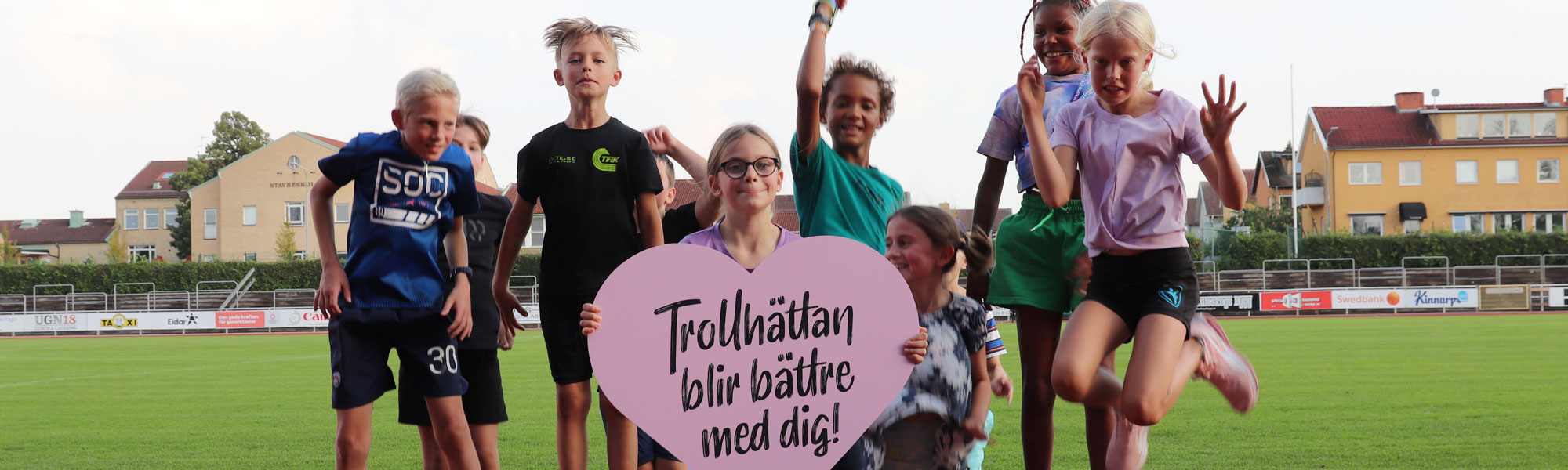 Nio barn som hoppar med hjärtformad skylt 