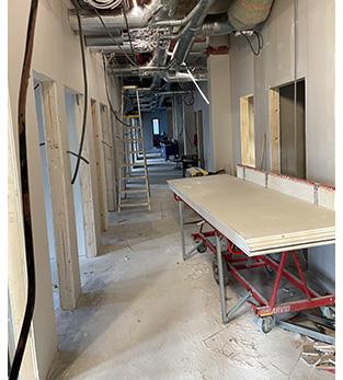 Bilden visar en korridor under uppbyggnad. En pall med gips står till höger i väntan på att monteras. 