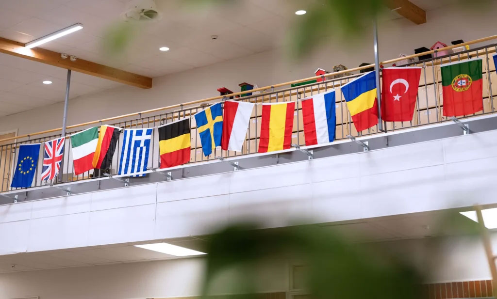 13 flaggor hänger bredvid varandra på ett räcke. Foto.