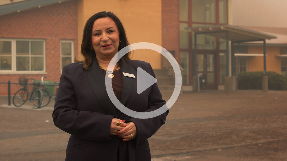 Almerisa Custovic, rektor p&aring; Paradisskolan tittar in i kameran. Ovanp&aring; bilden finns en play-symbol f&ouml;r att visa att en film visas om man klickar p&aring; bilden. Foto.