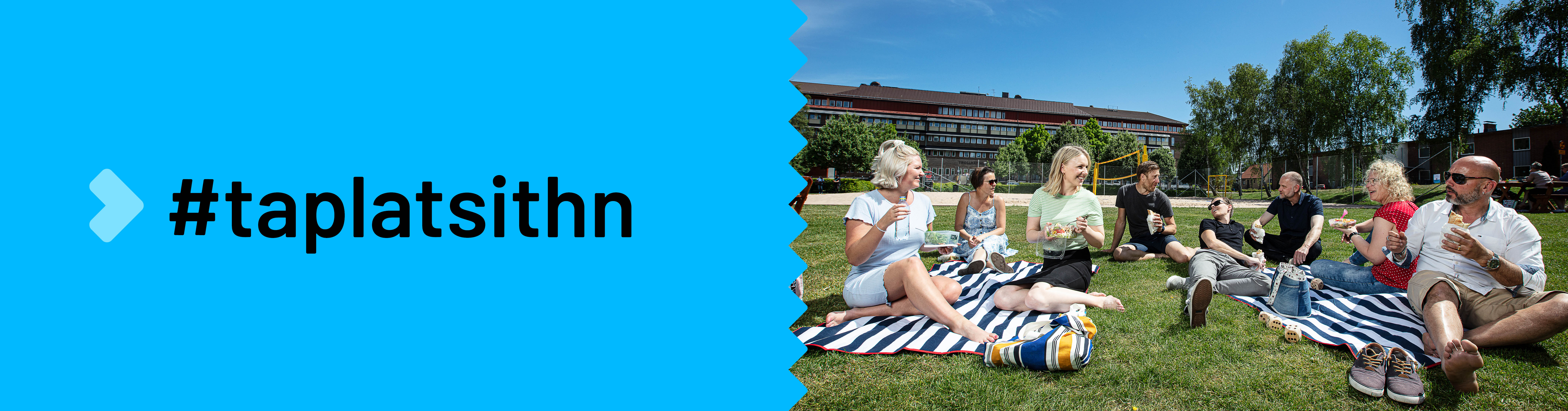 Sällskap som äter på picknickfilt i park. Text: #taplatsithn #gotrollhattan