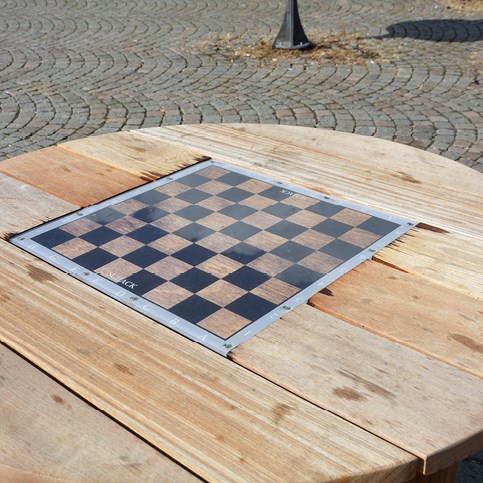 Bilden föreställer ett schack inbyggt i ett parkbord. 