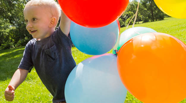 Barn som springer med ballonger i handen
