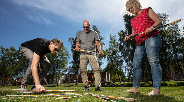 Tre personer som spelar stort utomhusplockepinn i en park