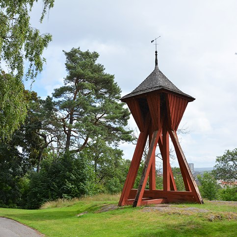 Bilden är ett fotografi på ett rött klocktorn. 