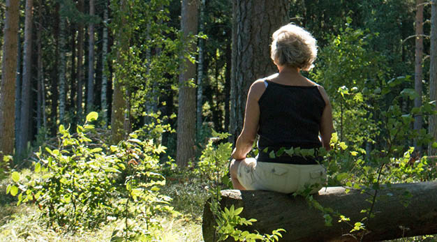 Kvinna som sitter på stock i skogen