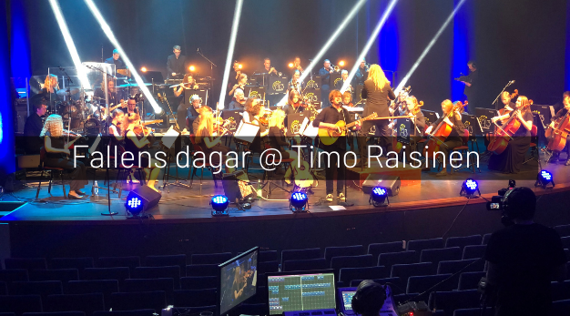 Bilden visar en konserthall med musiker och artisten Timo Räisinen