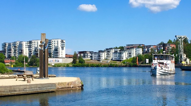 Trollhätte kanal med båt i förgrunden och bostadshus på Innovatumområdet i bakgrunden