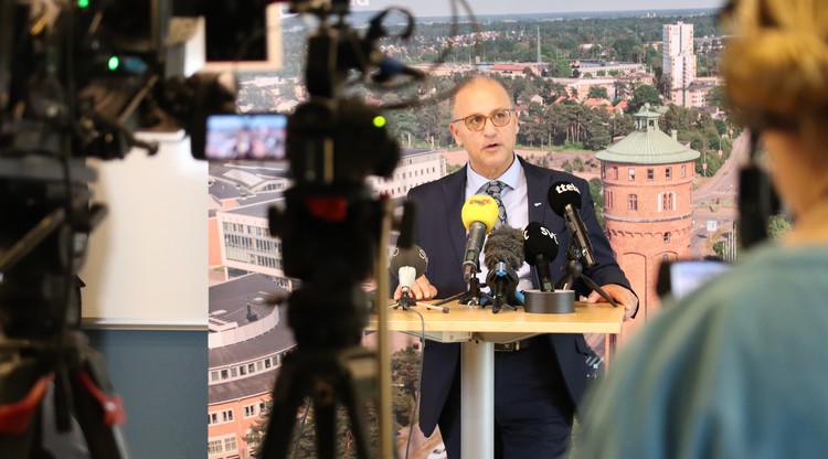 En man talar till journalister och kameror under en presskonferens