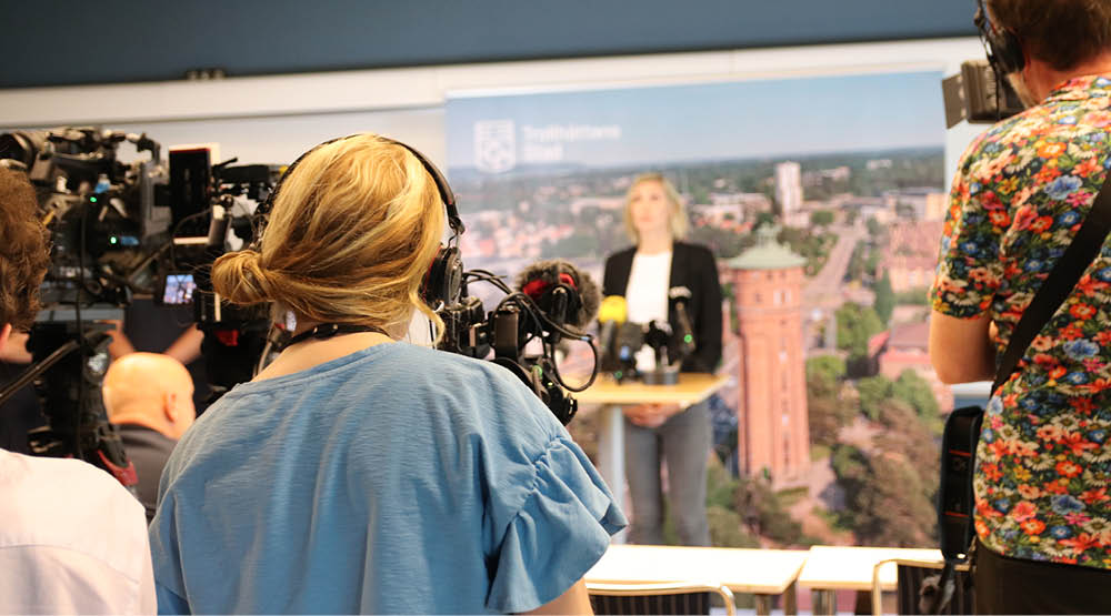 Människor bakom kameror riktade mot presskonferens.