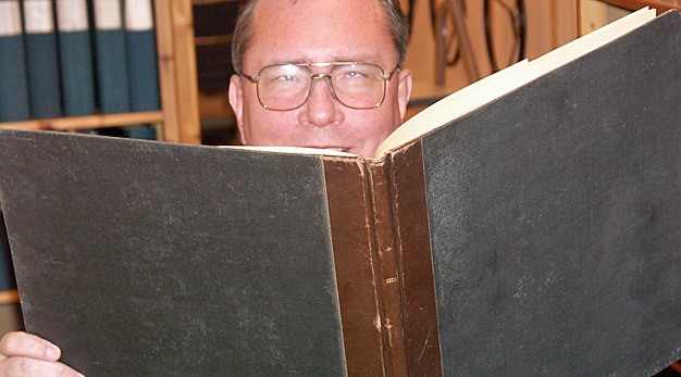 Sven-Åke på Arkivet kikar upp över en bok
