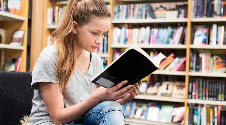 Tjej läser bok på bibliotek