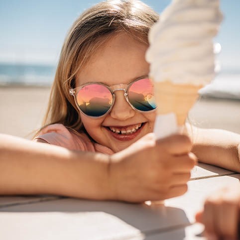 Flicka i solglasögon som äter glass