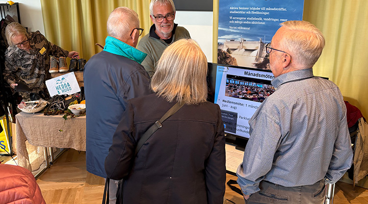 Bild på herrar som pratar med utställare på en seniormässa.