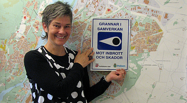 Gigi står mot en vägg och håller upp skylt som det står grannar i samverkan på