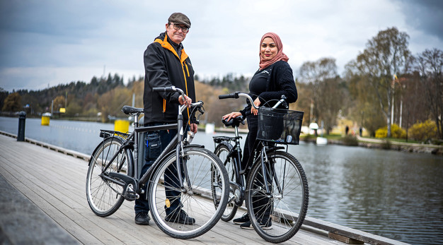 Två personer från hemtjänsten står vid varsin cykel intill en kanal.