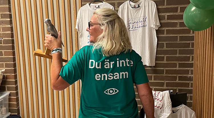 Kvinna står med ryggen mot kameran med budskapet "du är aldrig ensam"