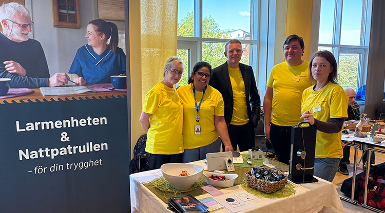 En grupp människor i gula t-shirts i en mässhall som har budksapet "larmpatrull" på en roll up.