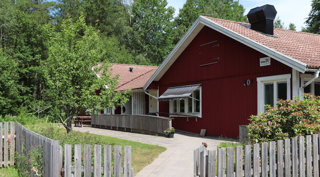 En enplansvilla med staket runt omkring. I bakgrunden är det träd och skog.