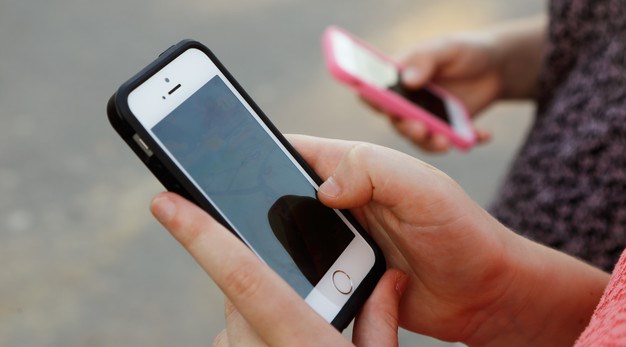 Två personer sitter ned och tittar på varsin smarttelefon