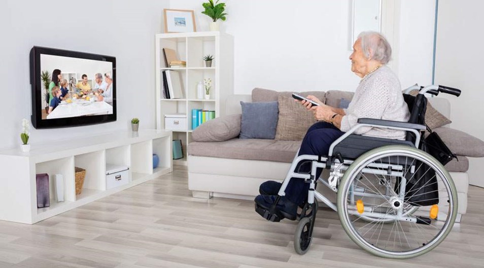 Äldre kvinna i rullstol i hemmet har ett videosamtal.