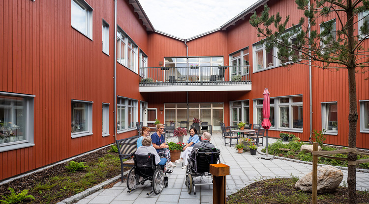 Personer sitter utomhus på uteplats och samtalar.