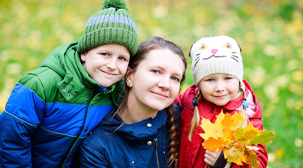 Mamma och två barn ute på hösten