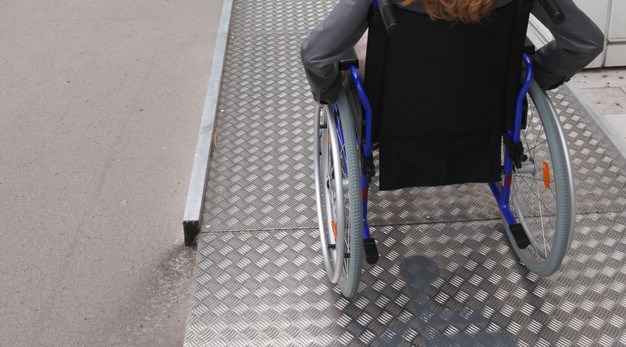 Person i rullstol på väg upp för en ramp.