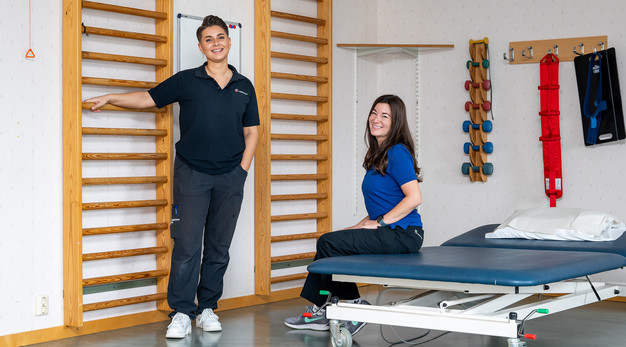 En fysioterapeut och arbetsterapeut i ett rum med rehabutrustning.