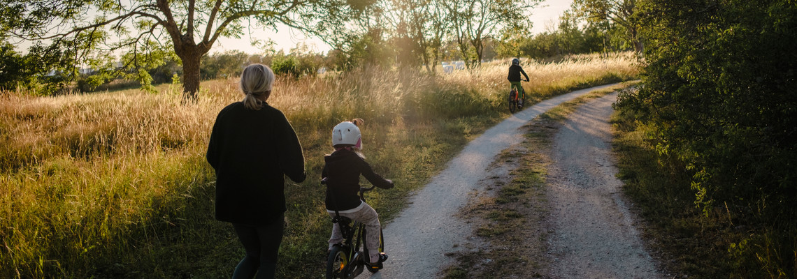 Mamma med två barn som cyklar på grusväg