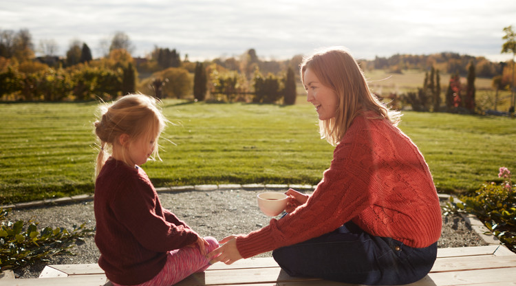 Mamma som sitter på altan med barn med skog i bakgrunden