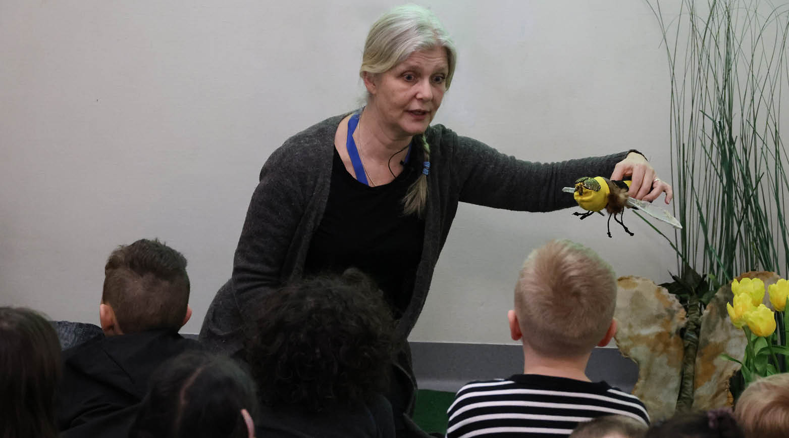 Anna med en fluga i handen och barn som tittar på föreställningen